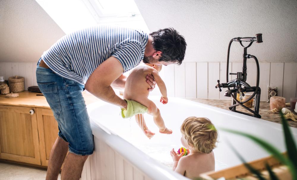 A dad giving two young boys a bath