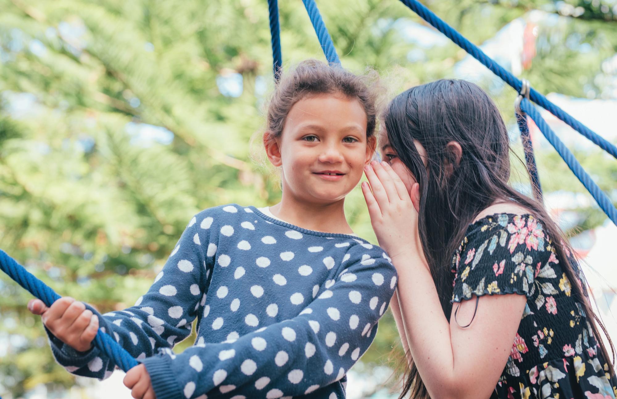 Two young school girls whispering to each other